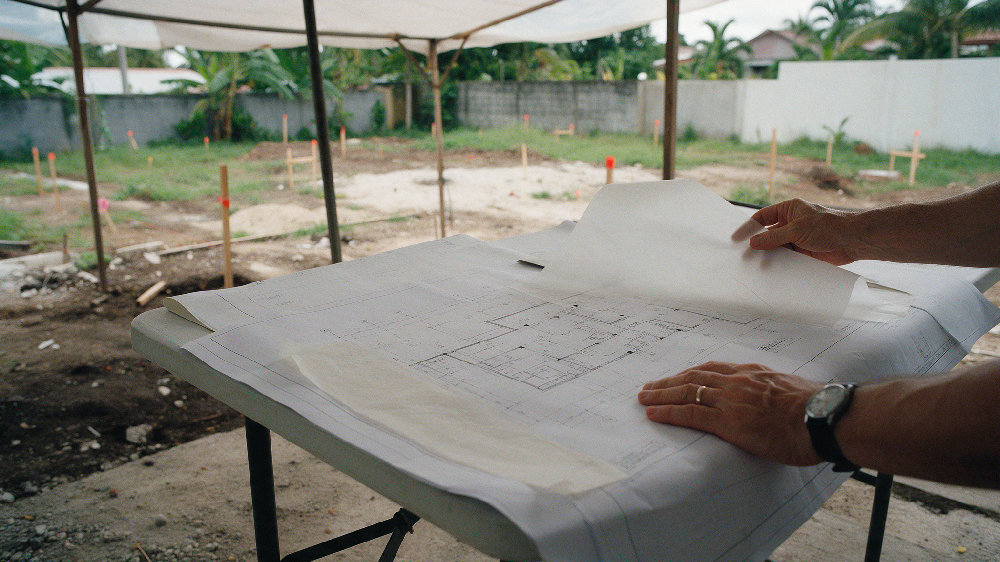 Architect reviewing site drawings on a tropical lot